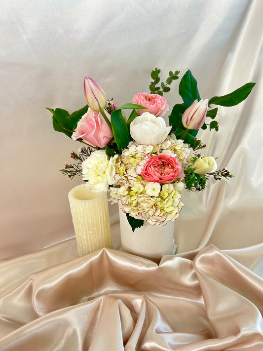 A white, pink, and purple floral bouquet from Dolci Fiori Florist in a tall white vase.